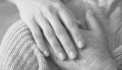 Mano di un adulto e di un anziano che si intrecciano