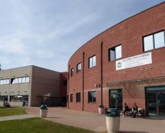 Palazzina grigia, palazzina mattoni rossi, vialetto, prato, cestini per i rifiuti