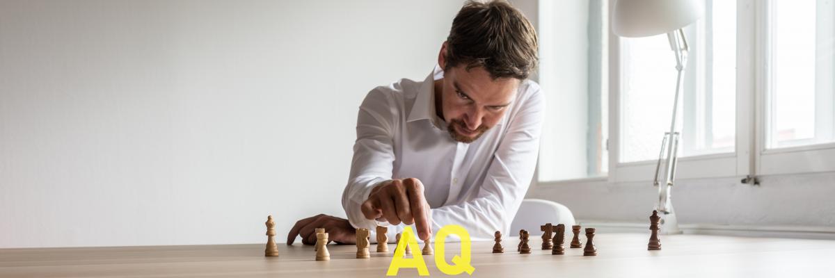 persona che muove una pedina degli scacchi con scritta AQ in sovra-impressione